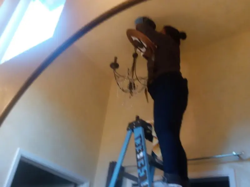 Electrician installing a chandelier in a Woodbury residence